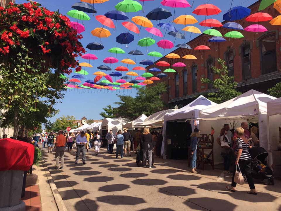 A street with umbrellas hanging overhead.